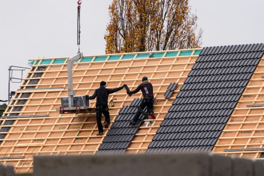 Dakdekkers leggen dakpannen op een nieuw dak