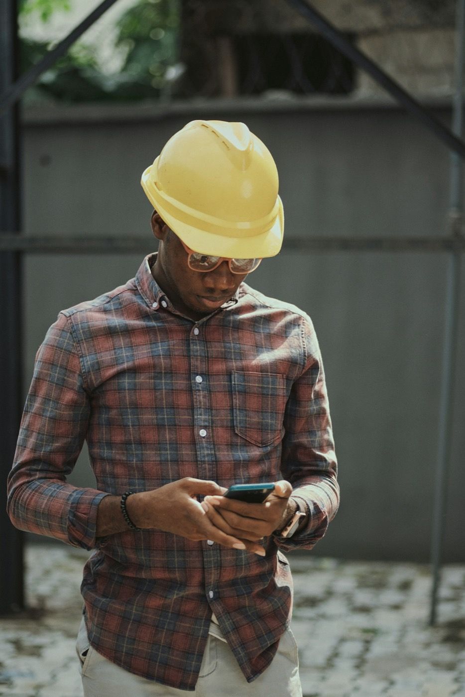 Vakman met bouwhelm kijkt op zijn telefoon