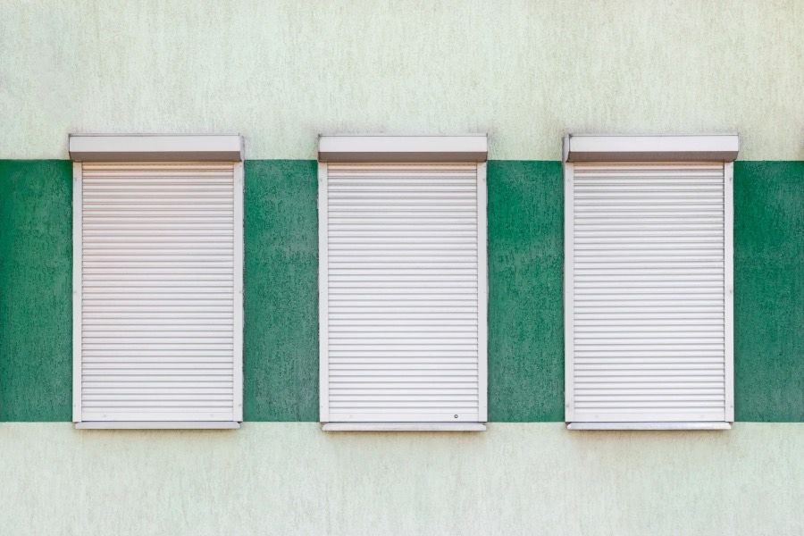Drie rolluiken, half neergelaten, in een gevel